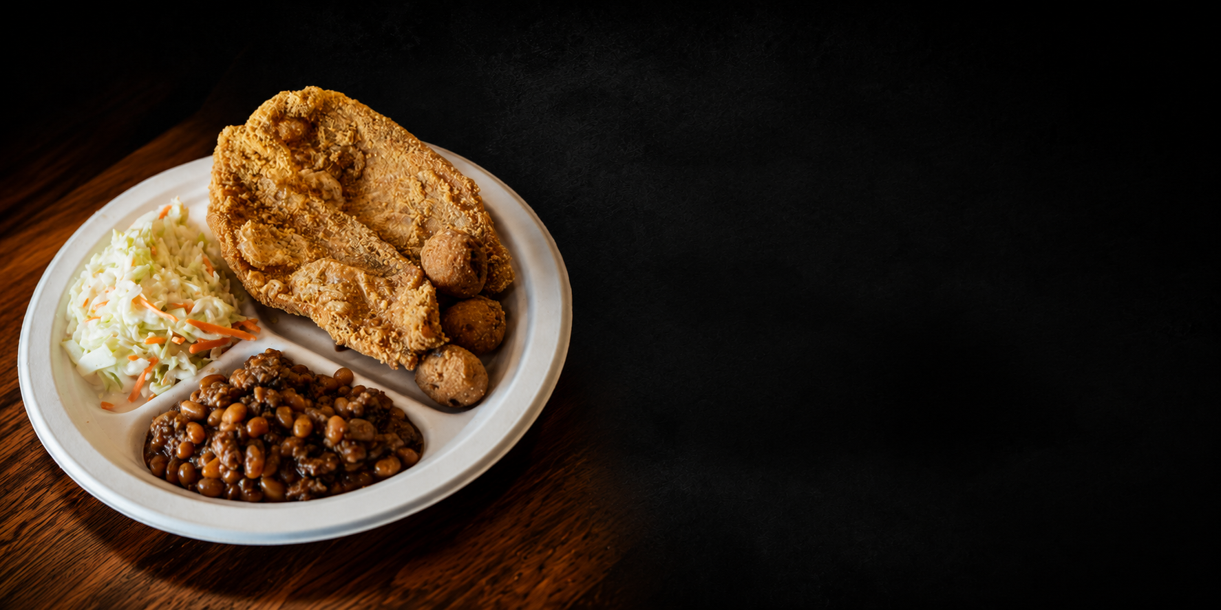 Fried catfish plate with coleslaw, baked beans and hushpuppies