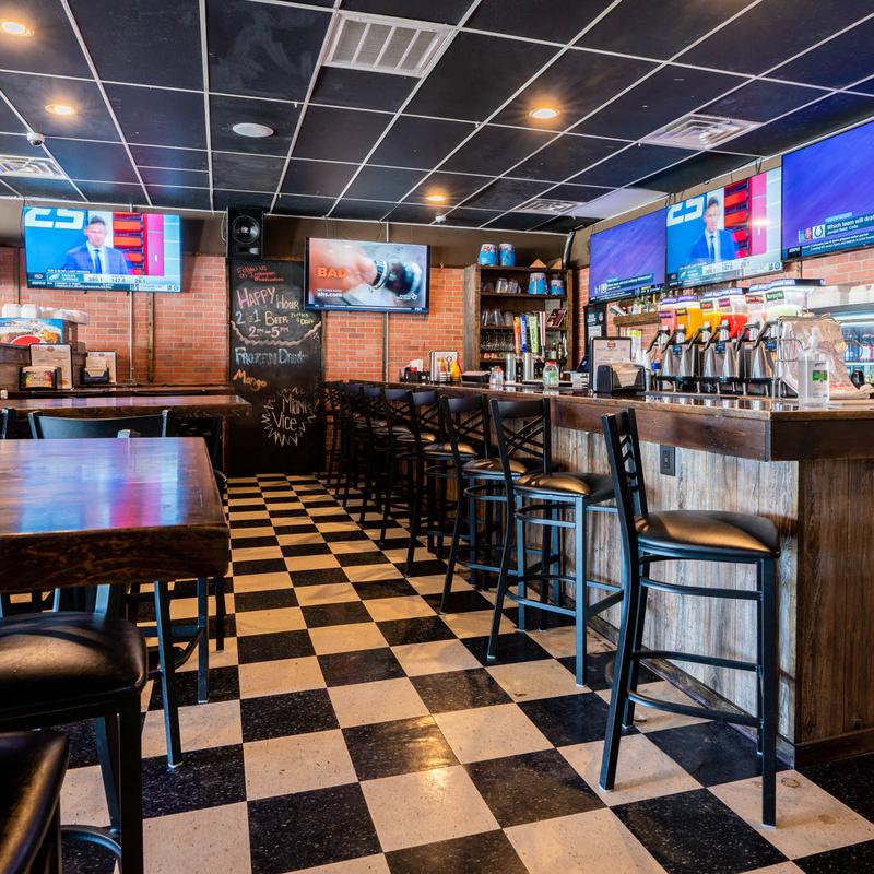 Bar seating with checkerboard floor and happy hour board